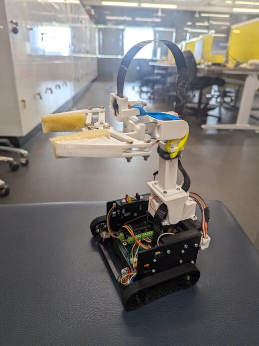 Real-life photo of the completed autonomous robot with the 3DOF arm extended and gripper holding a test item